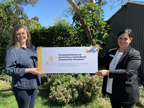 A photo of Prace Senior Manager Libby Barker and Sophie Nicolaou, Brand Manager at Commonwealth Bank Reservoir. They are holding up a large banner with the text "Congratulations on receiving a CommBank Community Donation".