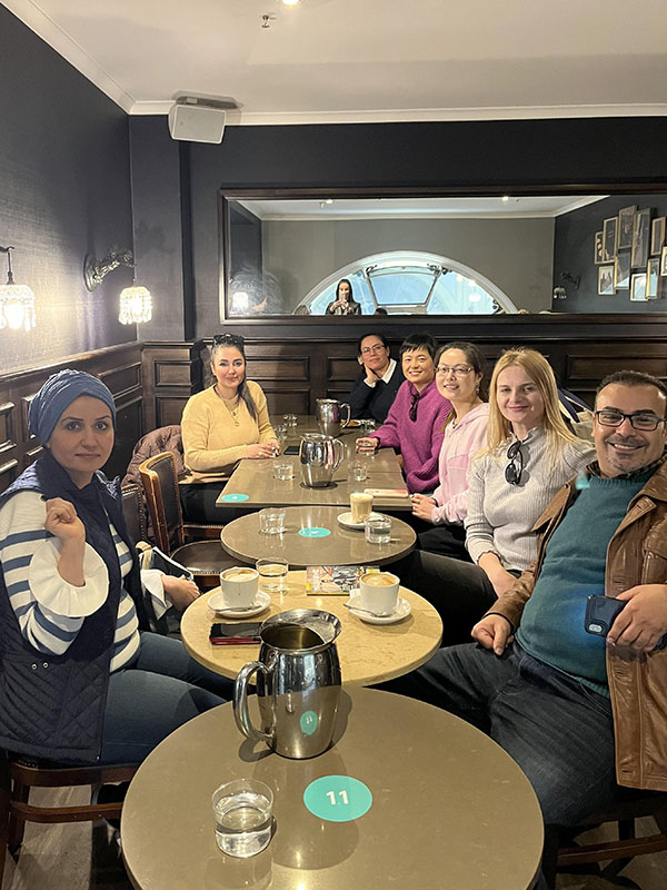 Seven Prace English language students sitting at tables in a cafe in Melbourne. They are drinking coffee.